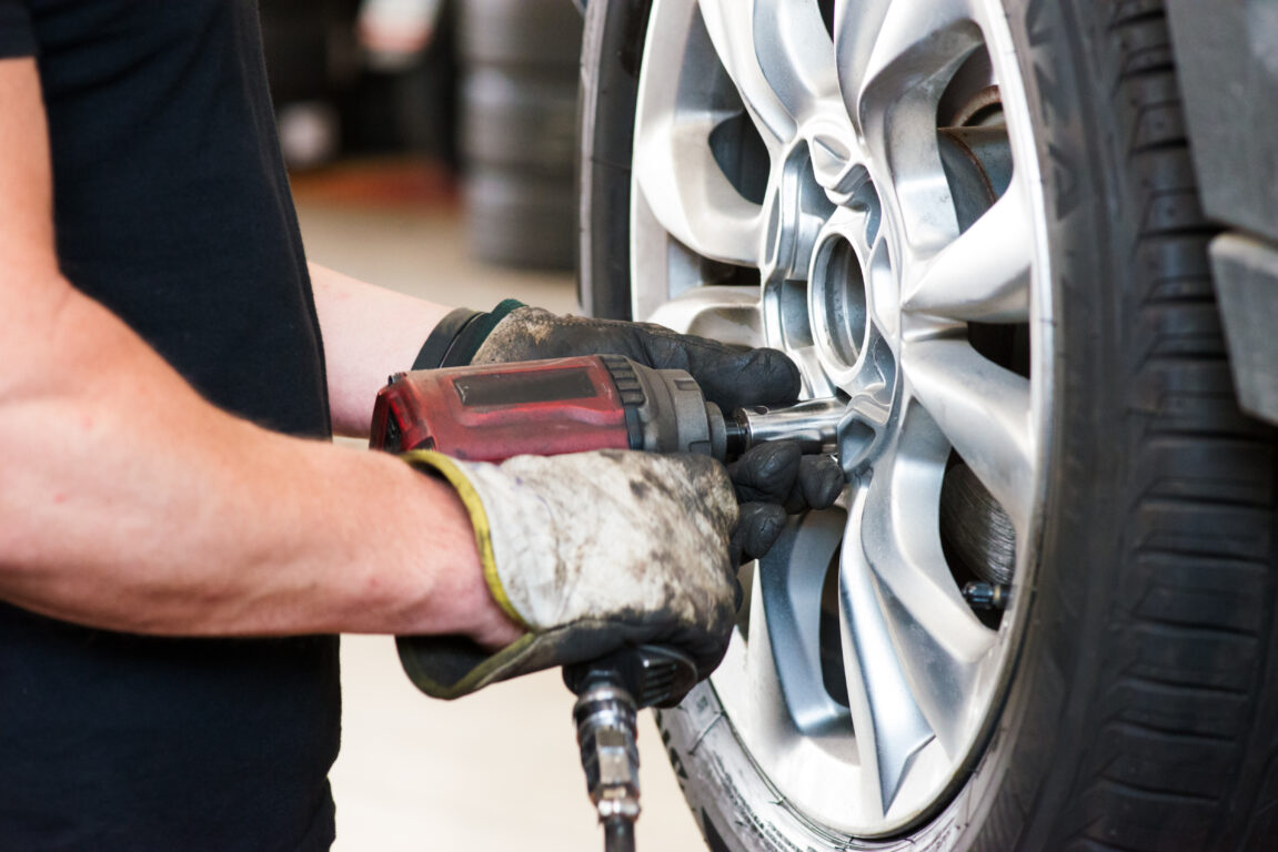 A man in a black shirt fitting a new tyre to a car.
